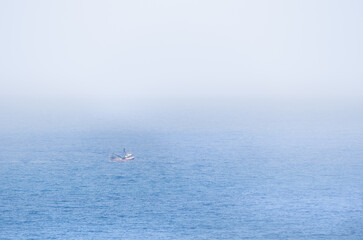 Single fishing boat in the Pacific ocean; misty day for a shrimp boat trip