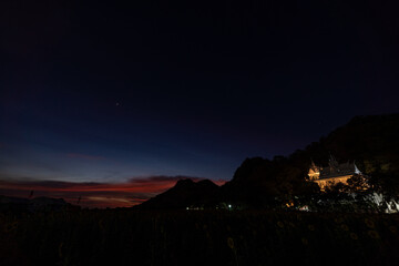  A vibrant scene featuring a glowing Buddhist temple nestled on a hill, with a sprawling sunflower field in the foreground under a beautiful sky in sunset. The contrast of beauty sunset and flowers