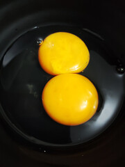 Bright yellow raw eggs placed on top of a black bowl