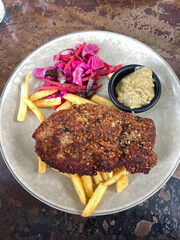 Pork schnitzel, pickled cabbage, and french fries.