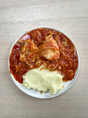 Chicken thigh in sauce and mash potato.