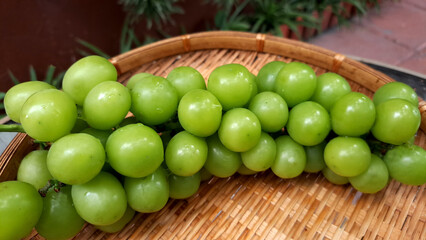 Blurred image of Muscat grapes placed on a bamboo basket.
