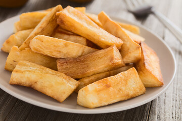 Homemade cooked and fried manioc cassava or yuca sticks (lat. Manihot esculenta) served on a plate (Selective Focus, Focus in the middle of the image)