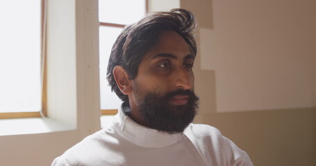 Focused fencer in white uniform preparing for match in bright room