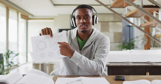 Explaining geometric drawings, young man wearing headphones during online school session - Powered by Adobe