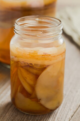 Homemade black tea kombucha or tea mushroom in glass jar with lots of scoby, a healthy fermented probiotic drink, on wooden table (Selective Focus, Focus on the front of the top scoby)