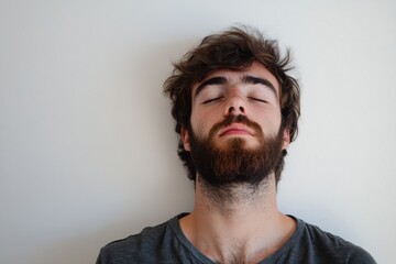 Obraz premium Relaxed Young Man with Beard and Closed Eyes in a Calm Setting