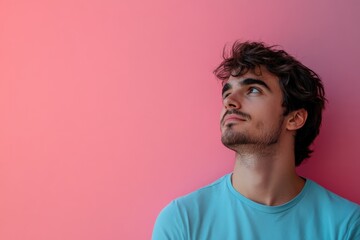 Fototapeta premium Thoughtful Young Man Gazing Upward Against a Soft Pink Background