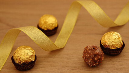 Gift image of luxury chocolate truffles, gold ribbon and wood grain background