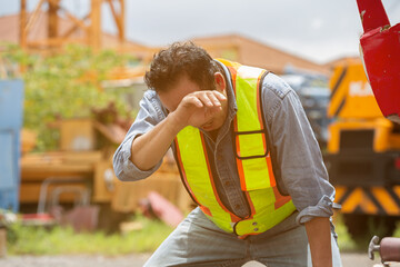 Senior Asian male construction builder tired and thirst of water at construction site. Construction...
