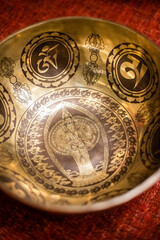 An exquisitely detailed Tibetan singing bowl featuring an engraved Avalokiteshvara deity surrounded by sacred symbols and intricate patterns, symbolizing compassion and spiritual practice
