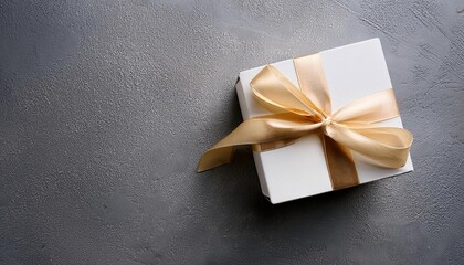 White Gift Box with Champagne Satin Ribbon on Concrete Background. Top View of Wedding Gifts with Copy Space