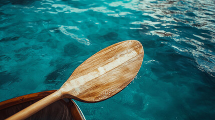 Wooden paddle above clear blue water during a peaceful canoe excursion