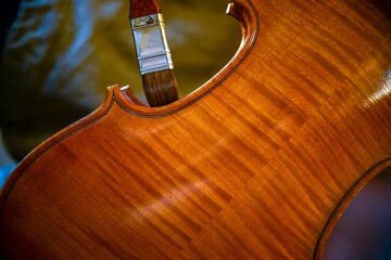 Luthier carefully applying varnish on a violin with brush © august.columbo