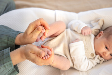 Parent holding in the hands feet of newborn baby. Mom holding baby feet.