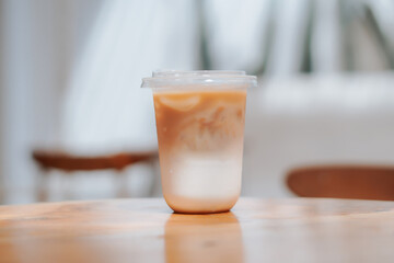 A refreshing glass of iced coffee sits on a wooden table, perfect for a sunny day. The image captures the drink's cool, refreshing appeal, perfect for cafes, food blogs, and lifestyle content.