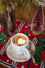 Close up of Hot coffee latte with latte art milk foam in cup mug with Xmas decors and Xmas tree baubles on wood desk Celebrating Merry Christmas and New year,Merry x-mas