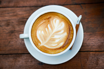 Top view of hot coffee latte with milk on wooden dining table in the morning.