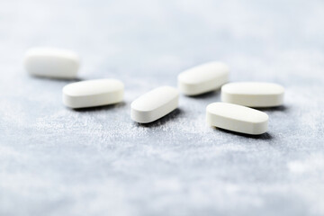 Arginine alpha-ketoglutarate (AAKG) tablets. Bodybuilding food supplements on wooden background. Soft focus. Close up. Copy space.