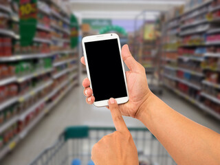 Man hand hold and touch screen smart phone, shopping center or super market background.