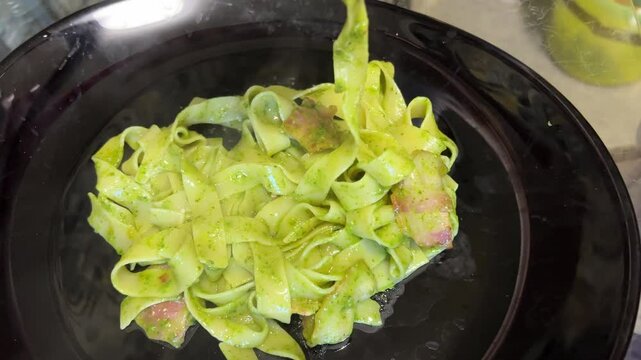 Serving pasta with pesto and stracciatella cheese in restaurant. Italian cuisine dish.