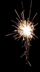 Fototapeta premium Burning sparkler emitting glowing light with bokeh light background, night, celebration