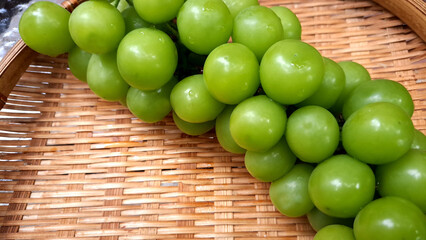 Image of Muscat grapes placed in a bamboo basket.