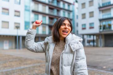 Fototapeta premium Happy woman raising hand while dancing in the city