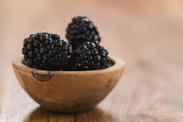 fresh blackberries in wood bowl on wooden table