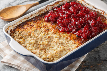 Maksalaatikko Finnish dish made from rice, chopped liver, butter, syrup, eggs, onions served with cranberry jam close-up in baking dish on table. Horizontal