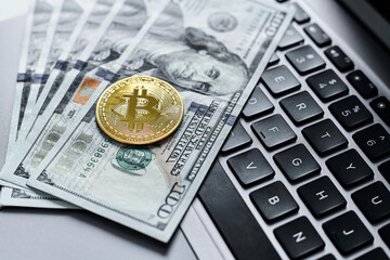 Gold bitcoin coins, us dollars, laptop keyboard close up.