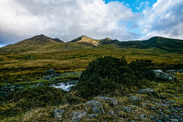 Breathtaking views of rugged mountains bathed in soft sunlight contrast with clear blue skies. A...