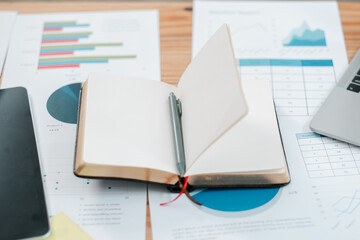 Open notebook on a desk with business charts and a laptop, ideal for themes of productivity, planning, and office work.