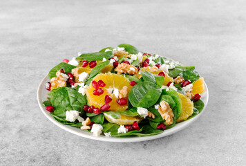 Christmas salad with oranges, lettuce, pomegranate, walnuts and feta cheese. Vegetarian green salad.