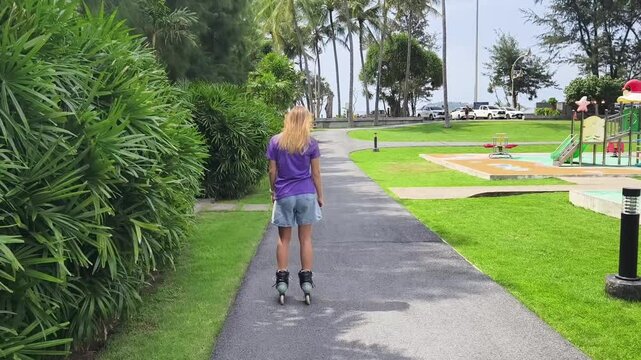 A woman is rollerblading gracefully on a road located in a park