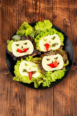 A black plate topped with lettuce and pumpkinshaped cheese