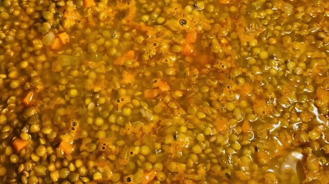 Italian traditional Christmas and festive meal: lentils with soffritto, slowly bubbling away in a pan. Real home cooking. Lentils are almost done. Vegetarian or vegan. Horizontal video. 
