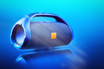 Blue portable wireless Bluetooth speaker, with reflection on a blue gradient background. Device for...