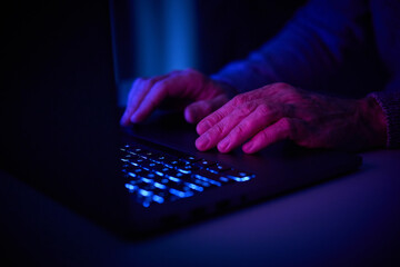 Male hands are typing on a laptop keyboard.