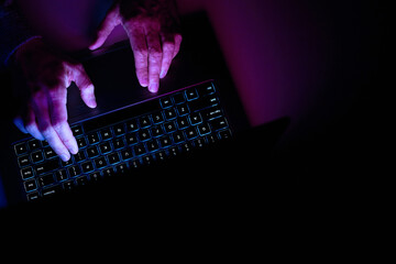 Male hands are typing on a laptop keyboard.