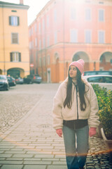 A young woman is leisurely strolling through the bustling city streets in a stylish winter outfit