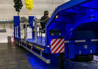 Naklejka premium The rear of a large truck with a low-bed platform designed for transporting heavy and oversized cargo. Equipped with a fastening system to secure the cargo during transportation.