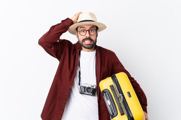 Traveler man man with beard holding a suitcase over isolated white background frustrated and takes...