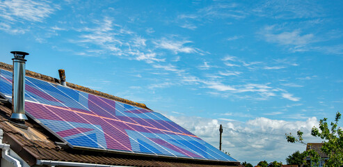 Panoramic picture of solar panels on a domestic roof with a Union jack flag overlaid across the panels. UK Solar energy concept with excellent copy space.