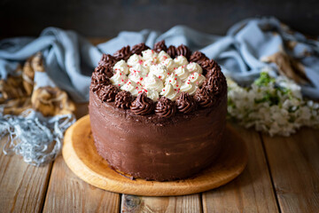 Chocolate cake with vanilla cream on a wooden table. Delicious chocolate birthday cake. Close-up.
