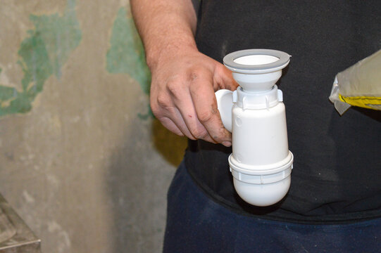 plumber's hands installing or tightening a white plastic siphon pipe under sink plumbing service DIY tutorials self-installation plumbing products home maintenance campaigns repair services homeowner