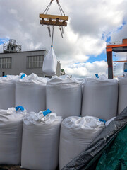 Loading big bags. Bags of bulk building materials stand in rows in an open warehouse. Bags of bulk construction materials in an open warehouse. The big bags are stacked. 