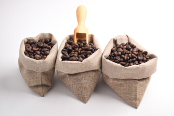 Sack and wooden scoop with roasted coffee beans isolated on white background.