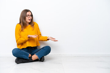 Young caucasian woman sitting on the floor isolated on white background with surprise facial expression