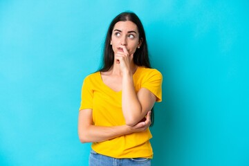 Young caucasian woman isolated on blue background having doubts and with confuse face expression
